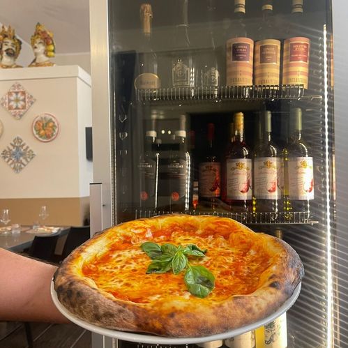 Vetrina dei vini e beverage e pizza margherita presso la Trattoria Pizzeria Anima e Cori